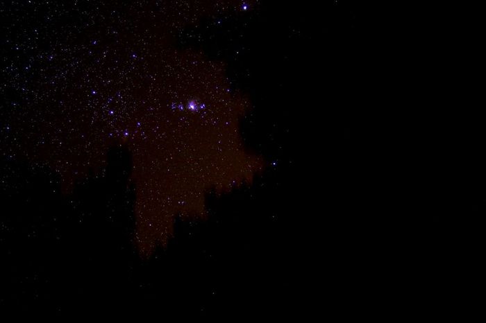 sous un ciel un peu perturbé un trou noir entre les branches des sapins